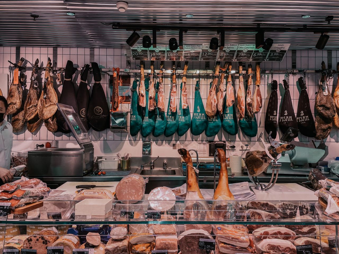 Explore a bustling butcher shop showcasing a diverse array of cured meats and hams.